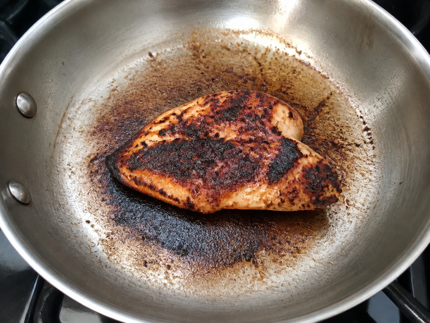 A chicken cutlet with burnt patches after searing too long