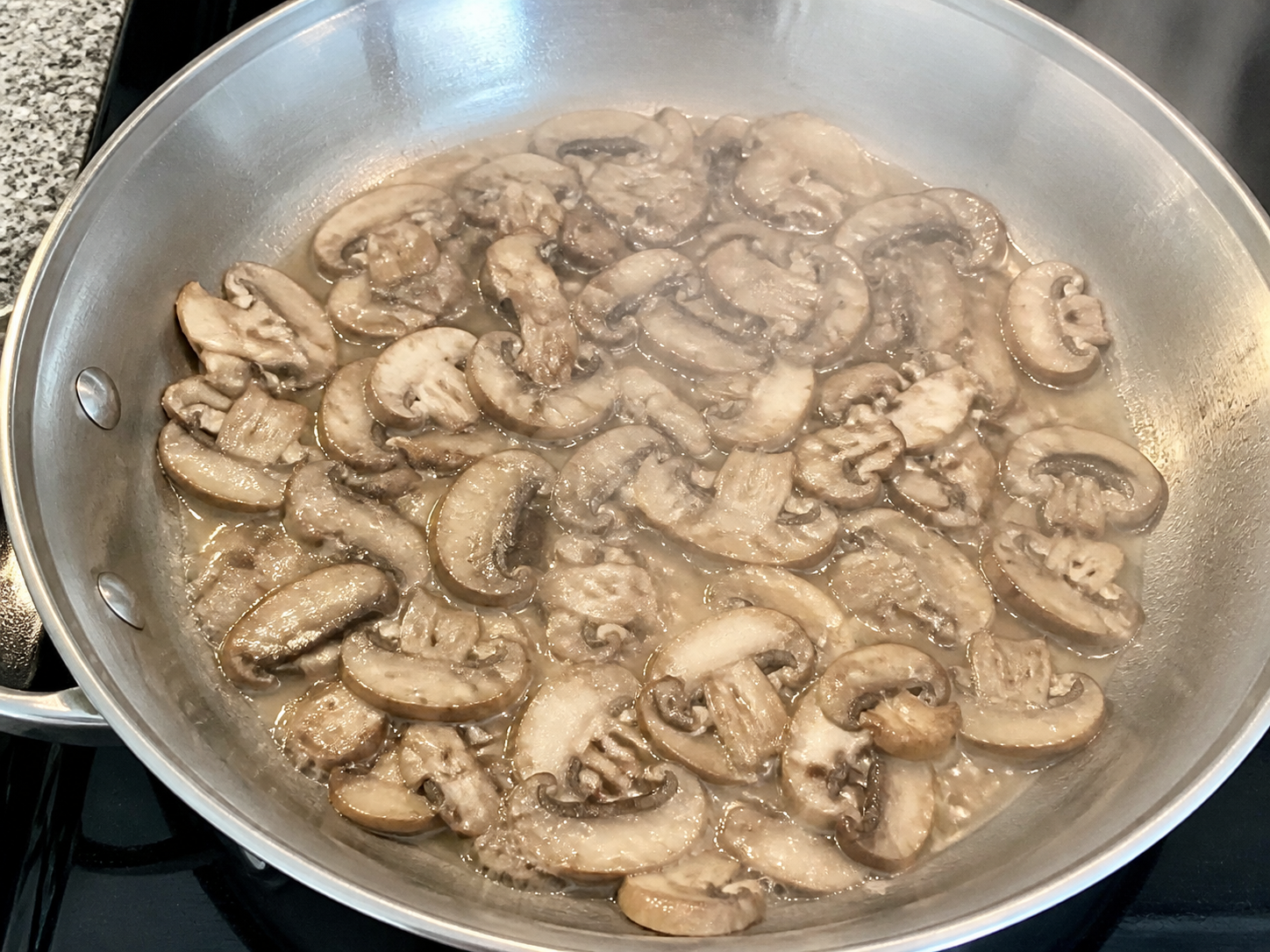 Pale mushrooms releasing moisture in a pan that is too cool